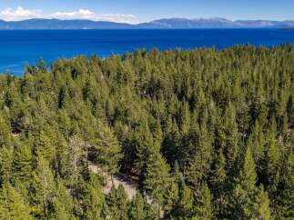 Experience the ultimate mountain lifestyle with this stunning aerial view of a property nestled amidst a dense pine forest.
