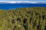 Experience the ultimate mountain lifestyle with this stunning aerial view of a property nestled amidst a dense pine forest.