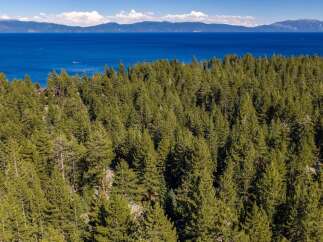 Experience the ultimate mountain lifestyle with this stunning aerial view of a property nestled amidst a dense pine forest.