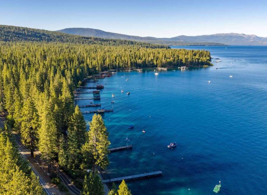 Experience the ultimate lakeside lifestyle with this stunning aerial view of a property nestled along a pristine, tree-lined shore.