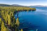Experience the ultimate lakeside lifestyle with this stunning aerial view of a property nestled along a pristine, tree-lined shore.