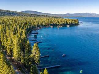 Experience the ultimate lakeside lifestyle with this stunning aerial view of a property nestled along a pristine, tree-lined shore.