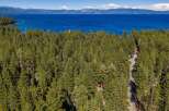 Discover serene living amidst a lush pine forest with breathtaking views of a vast blue lake and distant mountains.