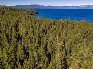 Experience the ultimate mountain getaway with this stunning aerial view of a secluded property nestled within a dense pine forest.