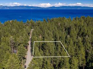 Nestled amidst a dense forest of pine trees, this property offers a serene escape with breathtaking views of a vast, blue lake and distant mountains.