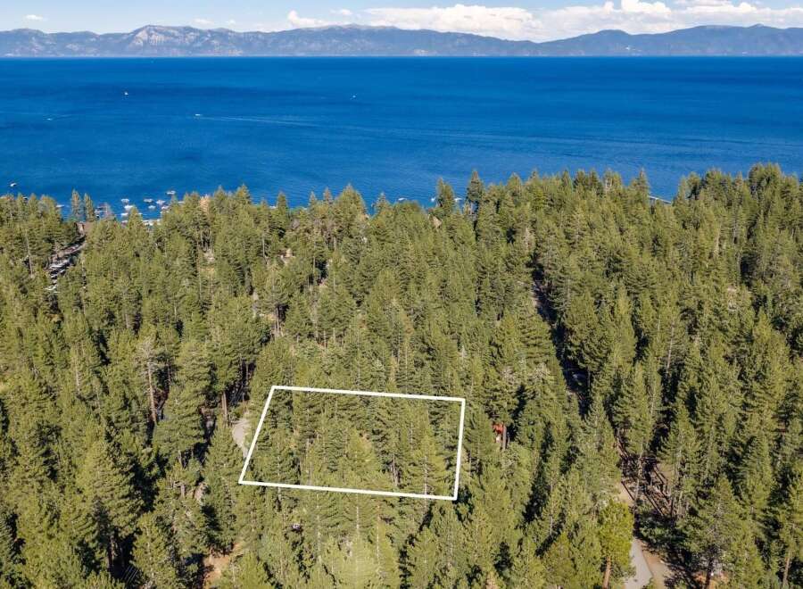Discover this stunning property nestled amidst a lush pine forest, offering breathtaking views of a vast, blue lake and distant mountains.