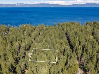 Discover this stunning property nestled amidst a lush pine forest, offering breathtaking views of a vast, blue lake and distant mountains.