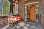 Welcome guests to this charming mountain retreat with a cozy wooden bench and vibrant accent pillows on the porch.