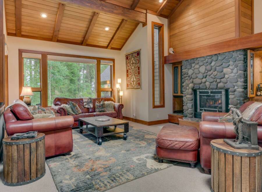 Experience rustic elegance in this stunning living room, featuring a grand stone fireplace and exposed wooden beams that create a warm, inviting atmosphere.