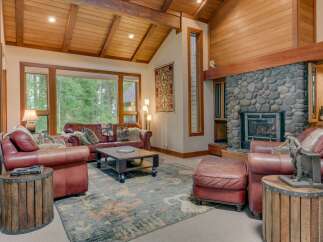 Experience rustic elegance in this stunning living room, featuring a grand stone fireplace and exposed wooden beams that create a warm, inviting atmosphere.