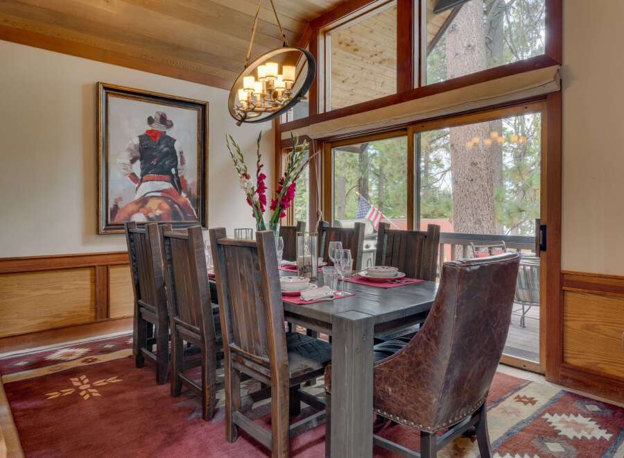 Experience rustic elegance in this inviting dining room, featuring a large wooden table set for a feast and surrounded by comfortable chairs.