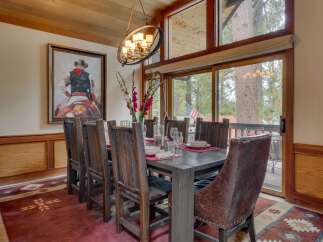 Experience rustic elegance in this inviting dining room, featuring a large wooden table set for a feast and surrounded by comfortable chairs.