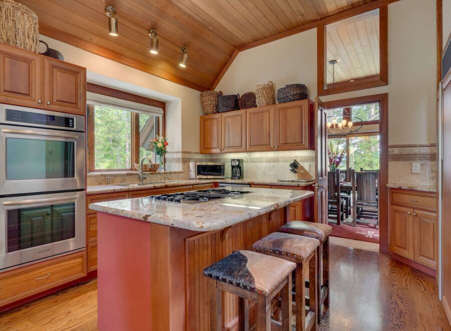 Experience the warmth of this inviting kitchen, featuring rich wood cabinetry and a stunning granite-topped island with bar seating.