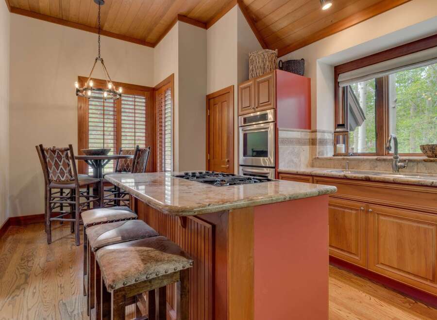 Experience rustic charm in this inviting kitchen, featuring a spacious granite-topped island with a gas range and comfortable seating.
