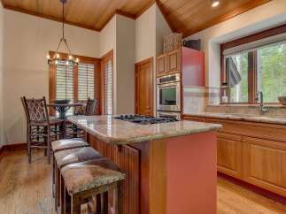 Experience rustic charm in this inviting kitchen, featuring a spacious granite-topped island with a gas range and comfortable seating.