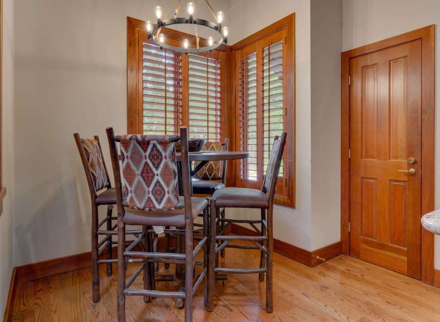 This cozy dining nook features a round table with four rustic bar stools, each adorned with a Southwestern-inspired patterned fabric.