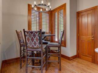 This cozy dining nook features a round table with four rustic bar stools, each adorned with a Southwestern-inspired patterned fabric.