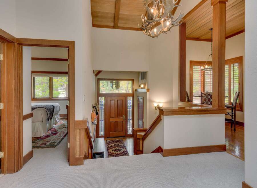 Step into this stunning entryway featuring a grand wooden staircase and a unique antler chandelier that adds a rustic charm.