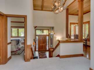 Step into this stunning entryway featuring a grand wooden staircase and a unique antler chandelier that adds a rustic charm.