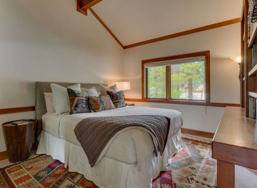 Experience cozy mountain living in this charming bedroom featuring a plush bed adorned with decorative pillows and a warm knit throw.