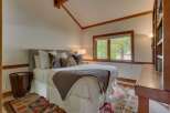 Experience cozy mountain living in this charming bedroom featuring a plush bed adorned with decorative pillows and a warm knit throw.