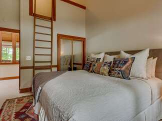 Experience rustic charm in this inviting bedroom, featuring a cozy queen-size bed adorned with decorative pillows and a plush throw.
