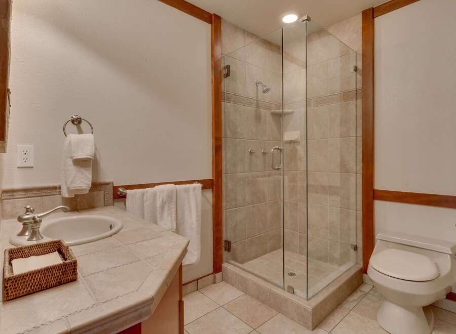 This bathroom features a spacious glass-enclosed shower with tiled walls and a built-in soap dish.
