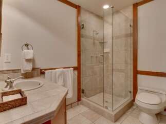 This bathroom features a spacious glass-enclosed shower with tiled walls and a built-in soap dish.