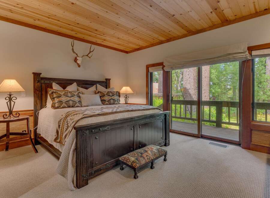 Experience rustic charm in this master bedroom, featuring a grand dark wood bed adorned with Native American-inspired pillows and a cozy throw.