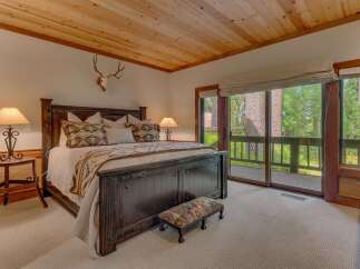 Experience rustic charm in this master bedroom, featuring a grand dark wood bed adorned with Native American-inspired pillows and a cozy throw.