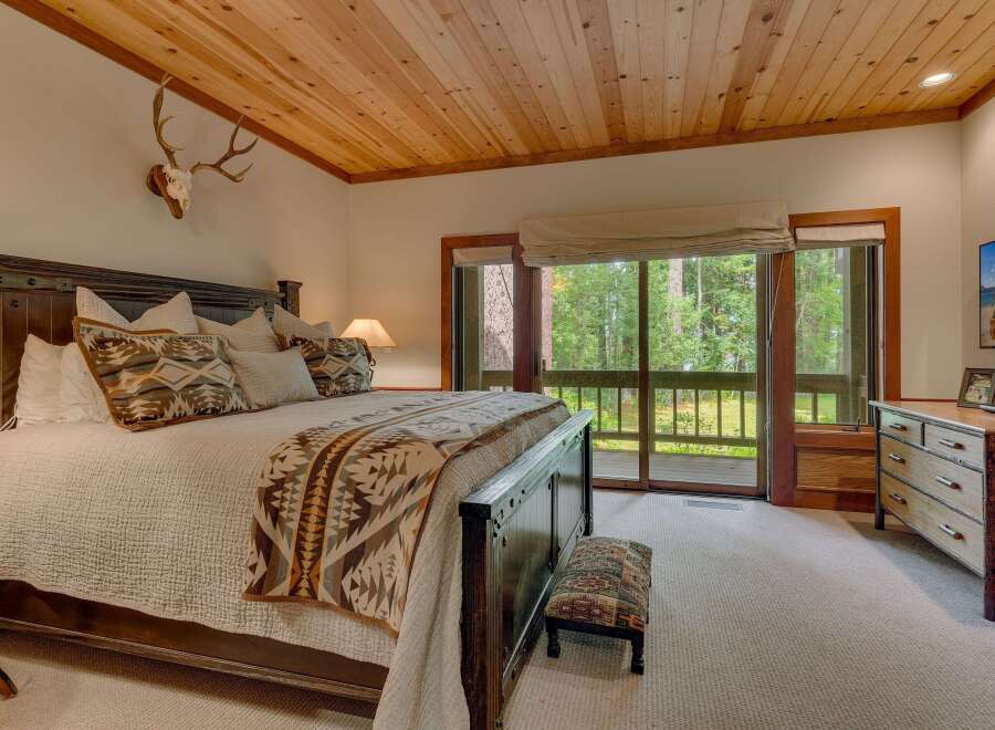 Experience rustic charm in this master bedroom, featuring a grand wooden bed adorned with patterned pillows and a cozy blanket.