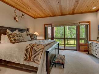 Experience rustic charm in this master bedroom, featuring a grand wooden bed adorned with patterned pillows and a cozy blanket.