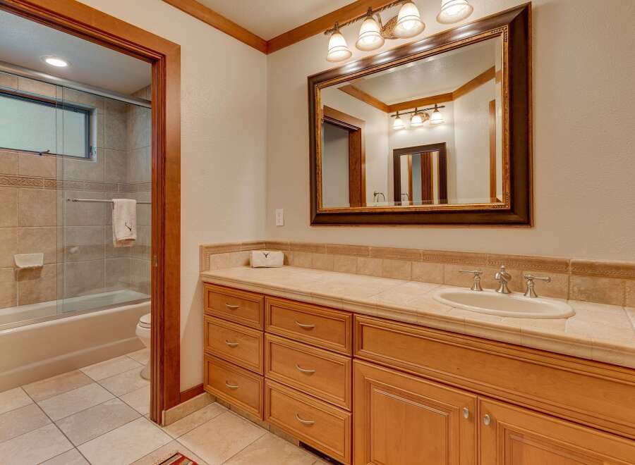 This bathroom features a spacious vanity with ample storage and a large mirror, perfect for your morning routine.