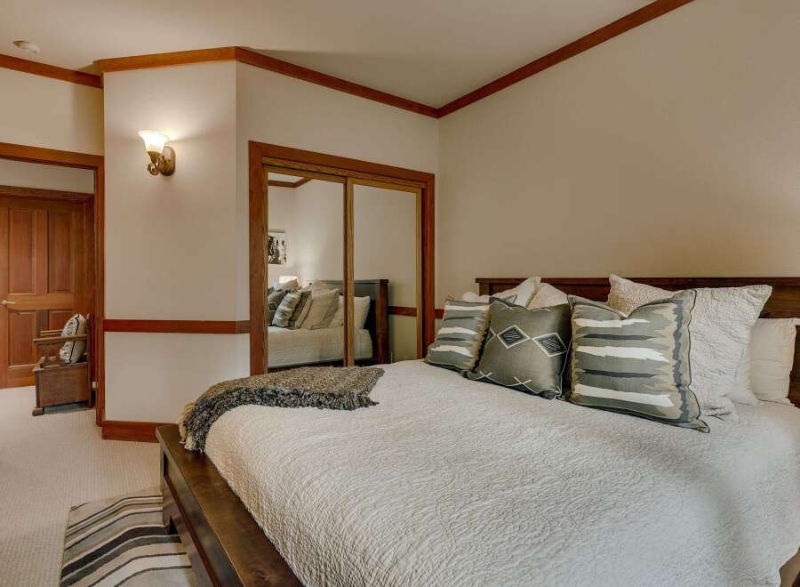 Experience ultimate comfort in this beautifully appointed bedroom, featuring a plush king-sized bed adorned with decorative pillows and a cozy throw.