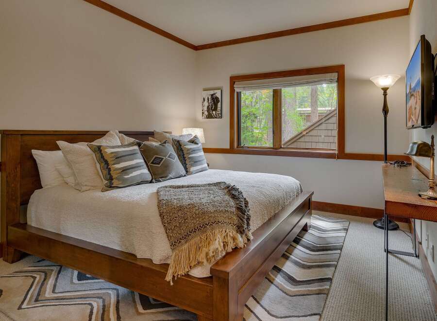 Experience rustic charm in this inviting bedroom, featuring a sturdy wooden bed adorned with plush pillows and a cozy throw blanket.