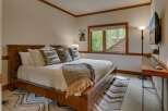 Experience rustic charm in this inviting bedroom, featuring a sturdy wooden bed adorned with plush pillows and a cozy throw blanket.