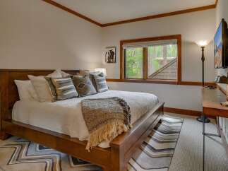 Experience rustic charm in this inviting bedroom, featuring a sturdy wooden bed adorned with plush pillows and a cozy throw blanket.