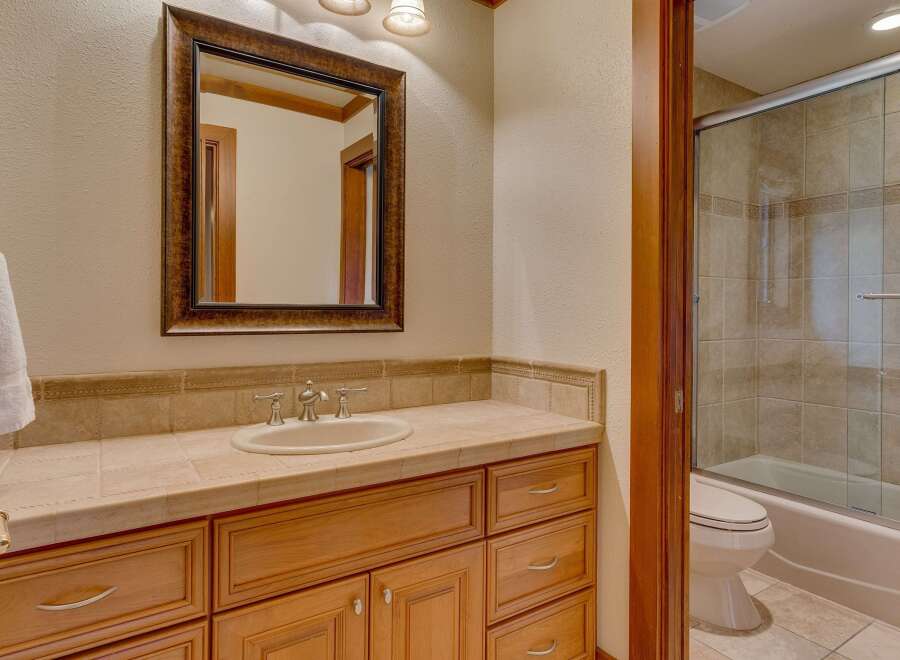 This bathroom features a spacious vanity with a tiled countertop and ample storage, complemented by a large, ornate mirror.