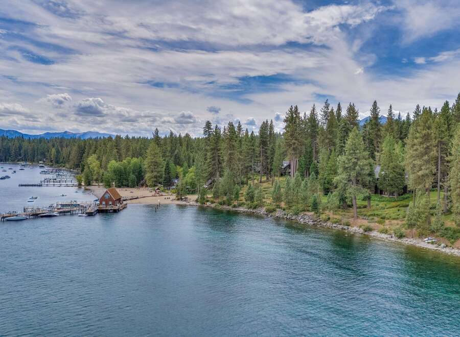 Experience lakeside luxury with this stunning aerial view of a property featuring a private dock with multiple boats and a charming boathouse.