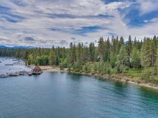 Experience lakeside luxury with this stunning aerial view of a property featuring a private dock with multiple boats and a charming boathouse.