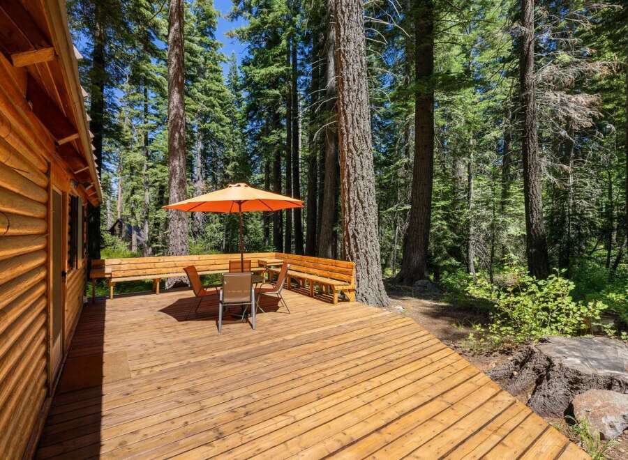 Enjoy outdoor living on this spacious wooden deck, perfect for entertaining or relaxing amidst a serene forest setting.