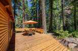 Enjoy outdoor living on this spacious wooden deck, perfect for entertaining or relaxing amidst a serene forest setting.