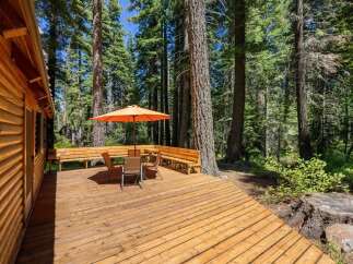 Enjoy outdoor living on this spacious wooden deck, perfect for entertaining or relaxing amidst a serene forest setting.
