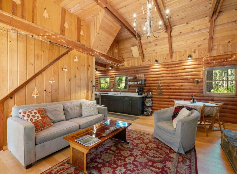 Experience rustic charm in this cozy cabin living space, featuring a comfortable sofa and armchair perfect for relaxing.