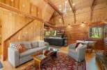 Experience rustic charm in this cozy cabin living space, featuring a comfortable sofa and armchair perfect for relaxing.