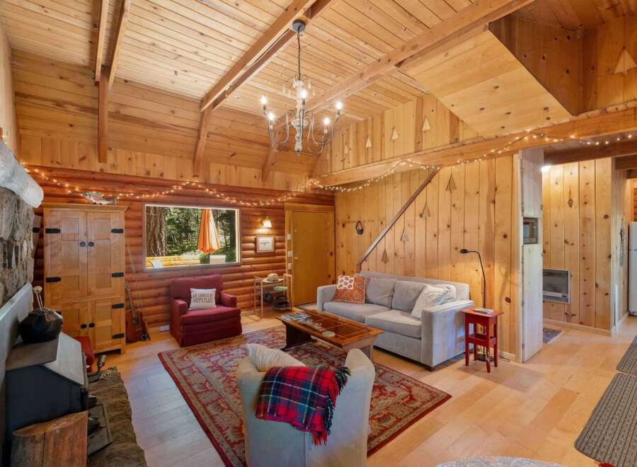 Step into a cozy cabin retreat featuring a warm, wood-paneled living area with a charming fireplace and rustic decor.