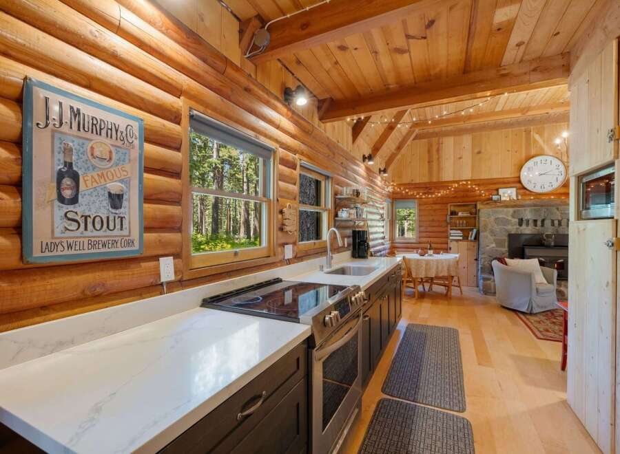 Experience rustic charm in this cozy log cabin kitchen, featuring a modern countertop and stainless steel appliances.