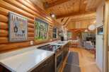 Experience rustic charm in this cozy log cabin kitchen, featuring a modern countertop and stainless steel appliances.