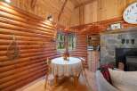 Experience rustic charm in this cozy log cabin dining area, featuring a quaint table set for two and illuminated by whimsical string lights.