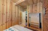 Experience rustic charm in this cozy cabin bedroom, featuring warm wood paneling throughout and a vaulted wood-beamed ceiling.
